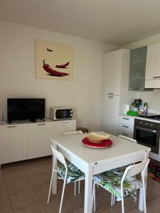 a white kitchen with a white table and chairs at Dimora Dafne in Policoro