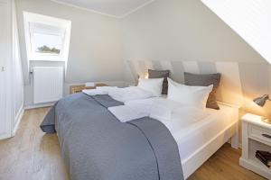 a bedroom with a large bed with white pillows at Auster Holte Hüüs in List