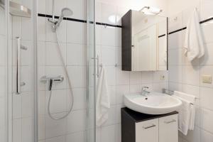 a white bathroom with a shower and a sink at Auster Holte Hüüs in List +24 photos
