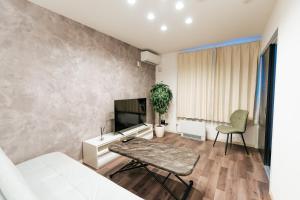 a living room with a couch and a tv at T-square旭大前I in Asahikawa