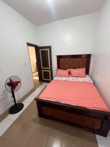 ein Schlafzimmer mit einem Bett mit roten Laken und einem Ventilator in der Unterkunft Janamaev in Jaunde