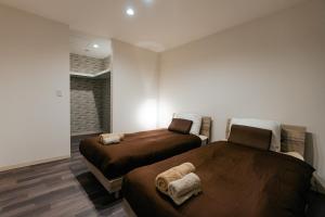 two beds in a room with white walls and wooden floors at T-square旭大前I in Asahikawa