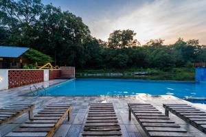 a swimming pool at a resort with trees in the background at Dandeli Kali Resort in Dandeli