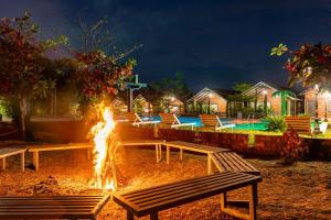 a fire pit with benches in front of a resort at night at Dandeli Kali Resort in Dandeli