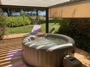 a large hot tub on a patio with a chair at Chambre d'Hôte de Rozessences in Chapelle-Voland