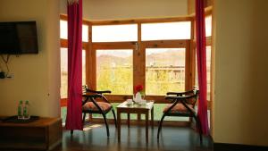a living room with two chairs and a table and a window at Hotel DE Suzain-Leh in Leh