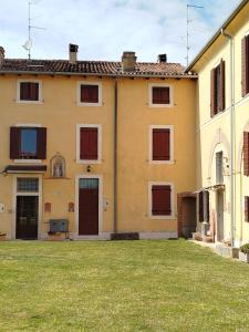 a yellow building with brown doors and a grass yard at B&Bee alla corte in Dossobuono