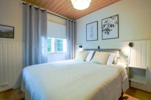 a bedroom with a white bed and a window at Alppitalo 3 as 3 in Tahkovuori