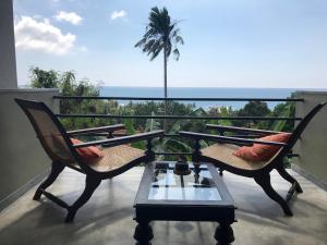 a balcony with two chairs and a table and a palm tree at Lara's place in Unawatuna