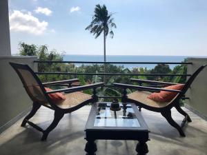 een balkon met 2 stoelen, een tafel en een palmboom bij Lara's place in Unawatuna