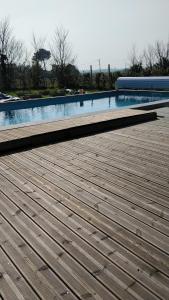 a large swimming pool with a wooden deck next to it at Les Lilas in Saint-Clair