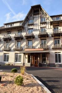 a large white building with balconies on a street at Hotel Le Continental in Forges-les-Eaux