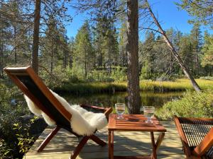 a deck with two chairs and a table with two glasses at Femund Canoe Camp in Drevsjø +14 photos