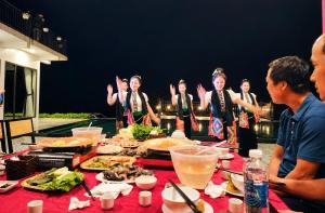 a group of people standing around a table with food at Sam Hotel Lào Cai in Pu Chu Chay