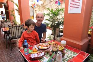 Um homem e um rapaz sentados à mesa com comida. em Posada Don Mario em Oaxaca City