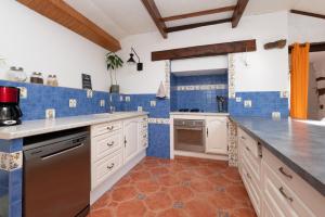 a kitchen with white cabinets and blue tiles at Maison familiale 10 personnes in Bannalec