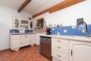 a kitchen with white cabinets and blue tiles at Maison familiale 10 personnes in Bannalec