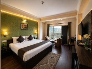 a hotel room with a bed and a balcony at Hotel Aachman Regency with Rooftop Terrace in Shimla