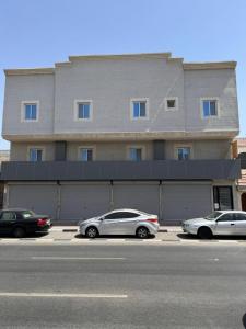 two cars parked in a parking lot in front of a building at Modren AD 23 in Dammam