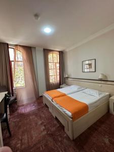 a bedroom with a bed and a desk and two windows at Hotel Cash in Tbilisi City