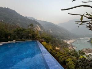 a swimming pool with a view of a river and mountains at ALOHA ON SACRED GANGES 2BHK Premium Ganga View Apartment with Infinity Pool in Rishīkesh