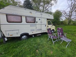 a white caravan parked in a field with two chairs at Bed and Breakfast Reestdal in Meppel