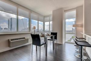 a dining room with a table and chairs and large windows at Global Luxury Suites at Newport in Jersey City