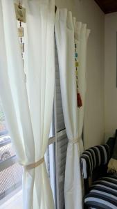 two white curtains in a room with a window at Rincón Esmeralda in Mercedes