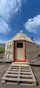 a yurt with a window in the middle of a field at Yurt camp Visit Kol-Suu in Kol-Suu