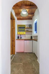 a kitchen with pink cabinets and a wooden ceiling at Marketos Windmill House in Tripiti