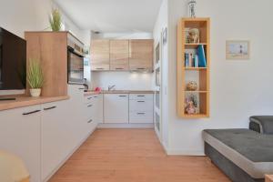 a small kitchen with white cabinets and a couch at Ferienhaus Keona Im Winkel in Dahme