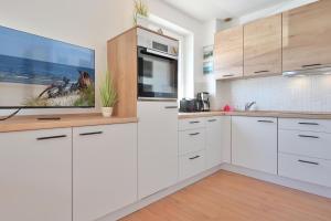 a kitchen with white cabinets and a tv on the wall at Ferienhaus Keona Im Winkel in Dahme