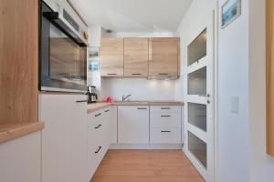a kitchen with white cabinets and wooden floors at Ferienhaus Keona Im Winkel in Dahme