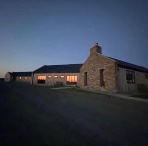 an old brick building with lights on at Housegarth in Twatt