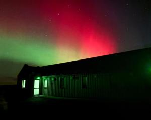 a green and red aurora over a building at night at Housegarth in Twatt