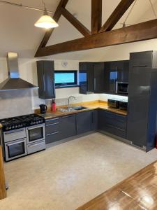 a large kitchen with black cabinets and a sink at Housegarth in Twatt