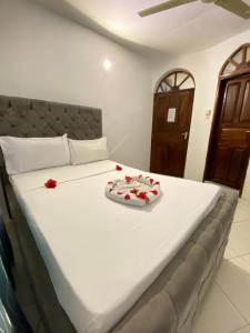a large white bed with red flowers on it at Hello Rafiki Hotel Stone town in Ngambo