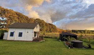 a house in a field with a fire in the background at Domek wakacyjny Domysłów in Domysłów