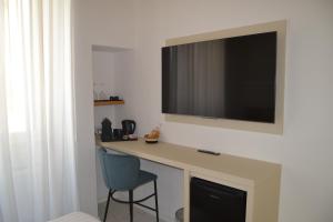 a room with a desk with a television on a wall at DuOr Suite & Rooms in Polignano a Mare