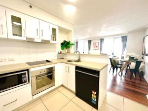 a kitchen with white cabinets and a table with chairs at Prime CBD High Rise Apartment in Cairns