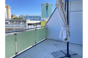 a white umbrella sitting on the balcony of a building at Misofi' in Bibione +2 photos