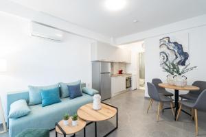 a living room with a blue couch and tables at Thalassa & Thalassa Prive Residential Complex in Ofrínion
