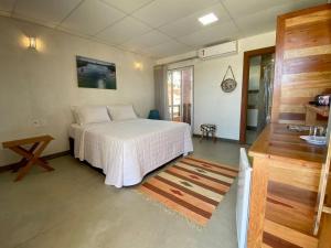 a bedroom with a white bed and a table at CAMALEÃO Ecopousada Ltda in Linhares