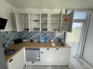 a kitchen with white cabinets and a counter top at Surf Osada, komfortowe domki w kameralnej okolicy nad samym brzegiem Zatoki Puckiej in Swarzewo