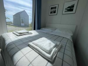 a bedroom with a bed with towels and a window at Surf Osada, komfortowe domki w kameralnej okolicy nad samym brzegiem Zatoki Puckiej in Swarzewo