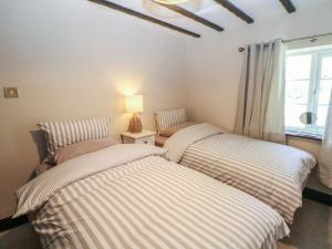 two beds in a room with a window at Pine Cottage in Hathersage