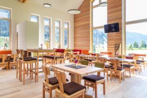 a restaurant with wooden tables and chairs and windows at Camping HOCHoben - ONLY EMPTY LOTS in Mallnitz +11 photos