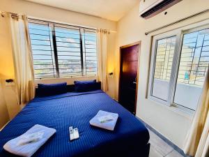 a bedroom with a bed with blue sheets and windows at Villa Govindaraj in Pondicherry