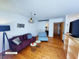 a living room with a purple couch and a tv at Bel Appartement Bad Kleinkirchheim in Bad Kleinkirchheim