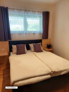 a large bed in a bedroom with a window at Bel Appartement Bad Kleinkirchheim in Bad Kleinkirchheim